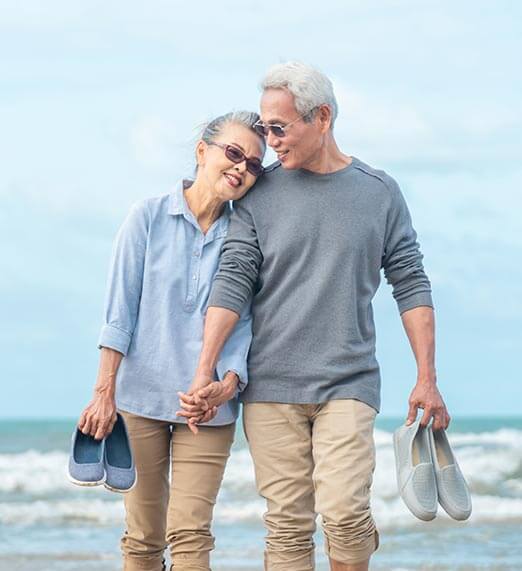 Older man and woman walking hand-in-hand on the beach