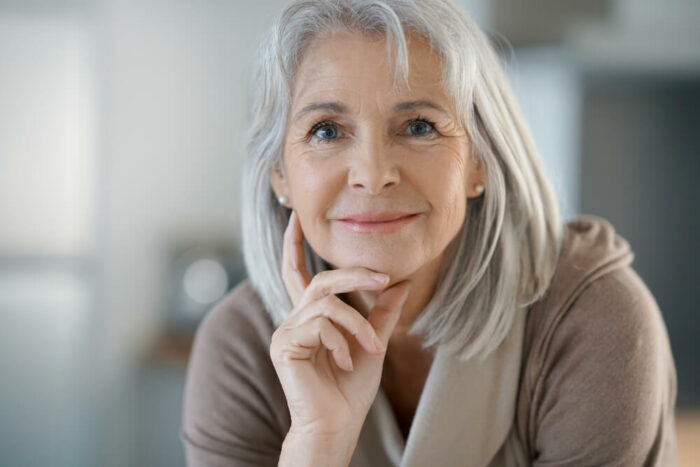 Senior woman looking at camera with hand on face