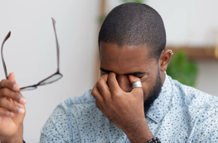 man rubbing eyes after taking off glasses